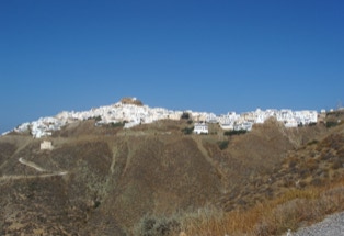 Blick von unten über karge Hänge auf die schneeweiße Hauptstadt auf der Spitze der insel anafi