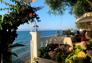 romantischer Tavernenblick mit exotischen Blumen am Strand von Korfu